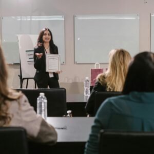 A business seminar showcasing a female presenter awarding certificates to attendees.