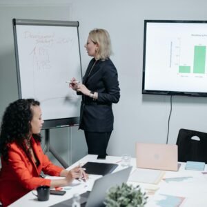 Businesswomen discussing strategy in modern meeting room with charts and analysis.